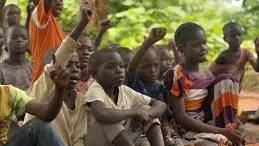 Children raising hands at a community gathering in Kenya